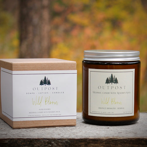 Wild Bloom beeswax candle with wooden wick shown with gift box in the beautiful fall forests of the Black Hills.