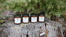 Load image into Gallery viewer, Four OUTPOST candles displayed on weathered pine stump. Cabin Time, Bourbon &amp; Bees, Heartwood and Cider House scents.