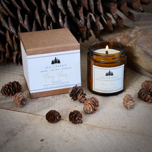 Load image into Gallery viewer, Ylang Ylang beeswax candle with burning wooden wick next to a kraft gift box