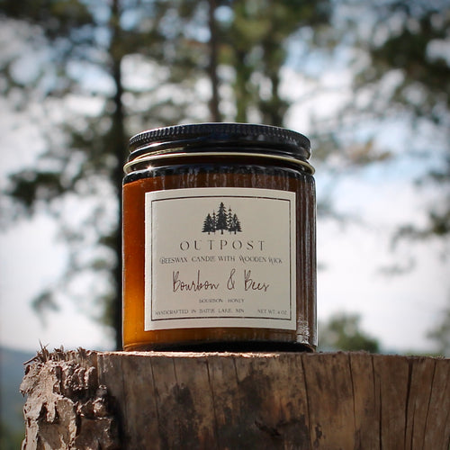 Bourbon and Bees beeswax candle in amber glass jar with wooden wick. Photo taken in West River forest during the autumn